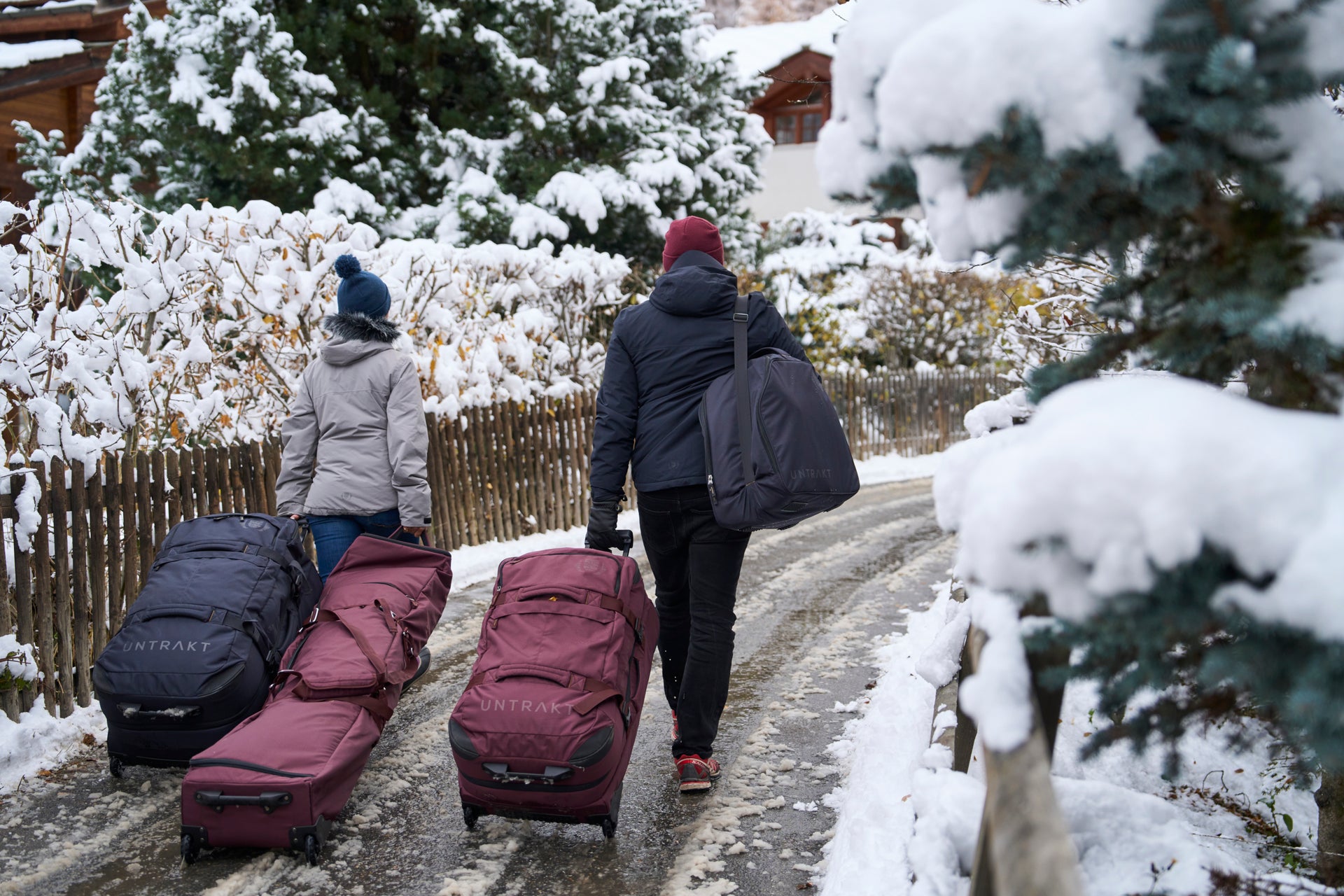 People walking with Untrakt ski bags in a snowy village